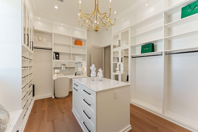 walk in closet with an inviting chandelier and light wood finished floors