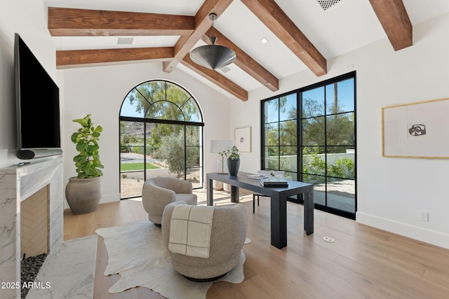 living area with a healthy amount of sunlight, vaulted ceiling with beams, light wood-style flooring, and visible vents