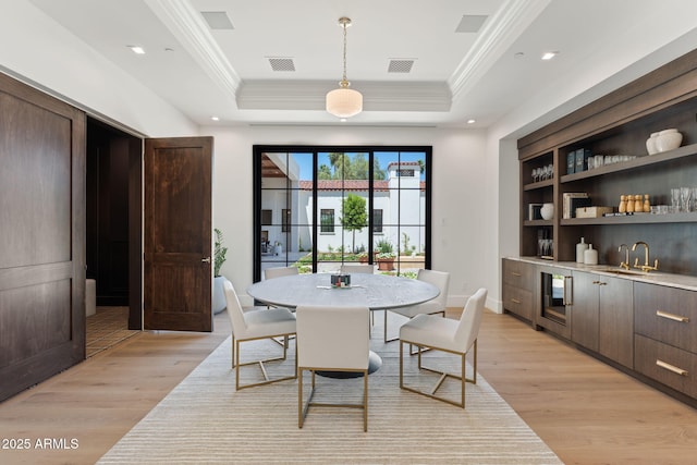 dining room with visible vents, light wood-style flooring, crown molding, and beverage cooler