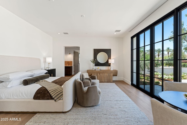 bedroom featuring visible vents, ensuite bathroom, baseboards, access to outside, and light wood-style flooring