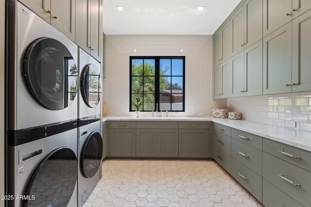 laundry room featuring cabinet space, light tile patterned floors, a sink, and stacked washer / dryer