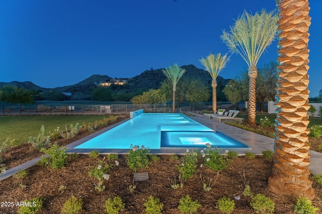 view of pool featuring a pool with connected hot tub, fence, and a mountain view