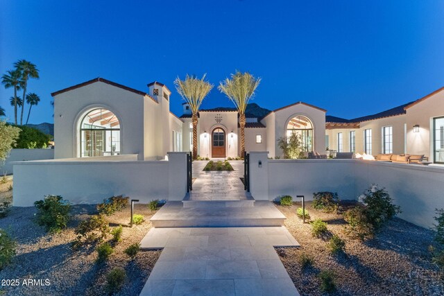 mediterranean / spanish-style home featuring a fenced front yard, a gate, and stucco siding