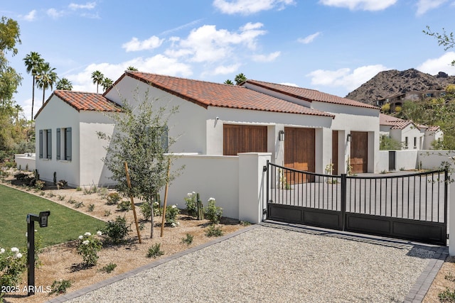 mediterranean / spanish-style home with fence, stucco siding, a gate, a mountain view, and a tile roof