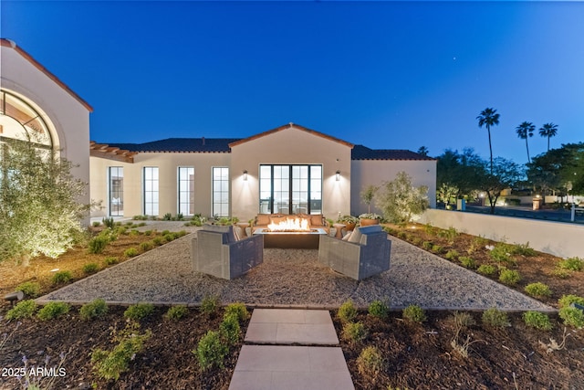 exterior space featuring stucco siding, a fire pit, a tiled roof, and a patio area