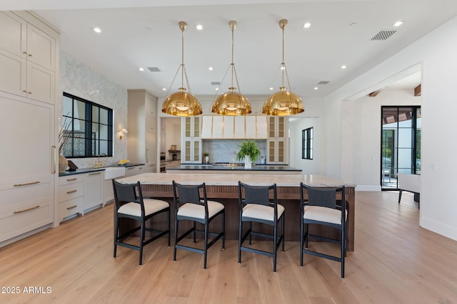 kitchen featuring backsplash, visible vents, and light wood-type flooring