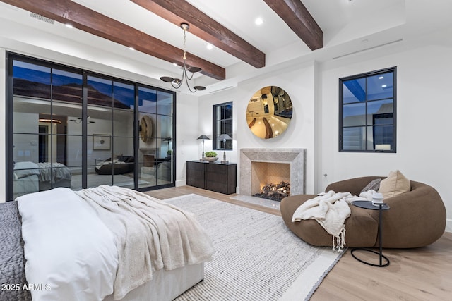bedroom with wood finished floors, beam ceiling, baseboards, access to outside, and a high end fireplace