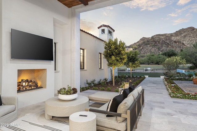 view of patio / terrace with fence, a lit fireplace, and a mountain view
