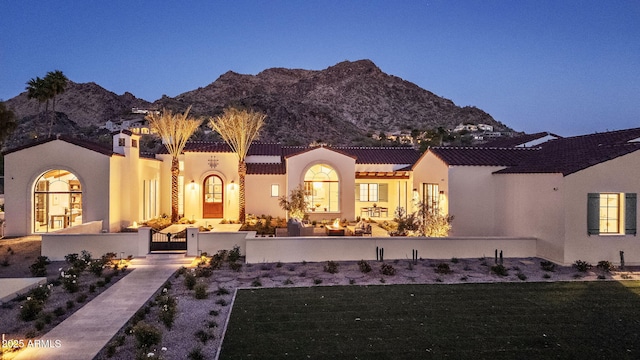 rear view of house featuring a tile roof, fence private yard, a mountain view, and stucco siding