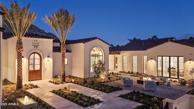 exterior space featuring an outdoor hangout area, a patio, stucco siding, and a tile roof