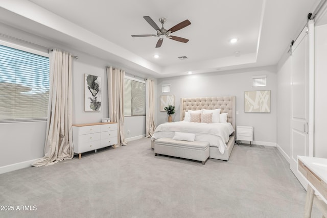 bedroom with a tray ceiling, recessed lighting, a barn door, light carpet, and baseboards