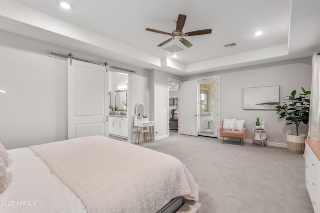 bedroom featuring a tray ceiling, visible vents, a barn door, light carpet, and baseboards