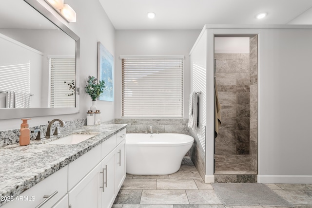 bathroom with a freestanding bath, tiled shower, vanity, and recessed lighting