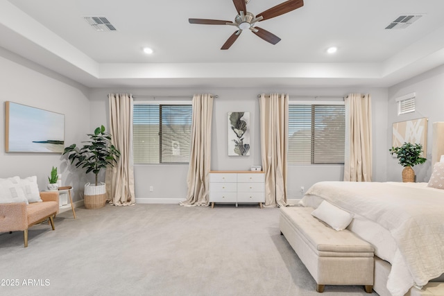 bedroom featuring light carpet, visible vents, and a tray ceiling