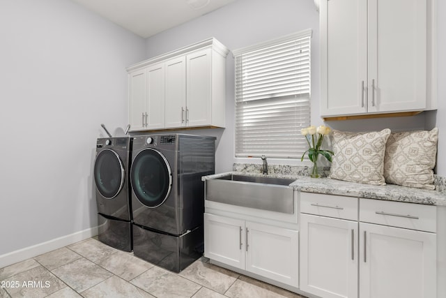 laundry area featuring light tile patterned floors, washing machine and dryer, a sink, baseboards, and cabinet space