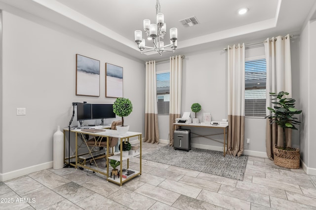 office area with visible vents, a tray ceiling, a chandelier, and baseboards