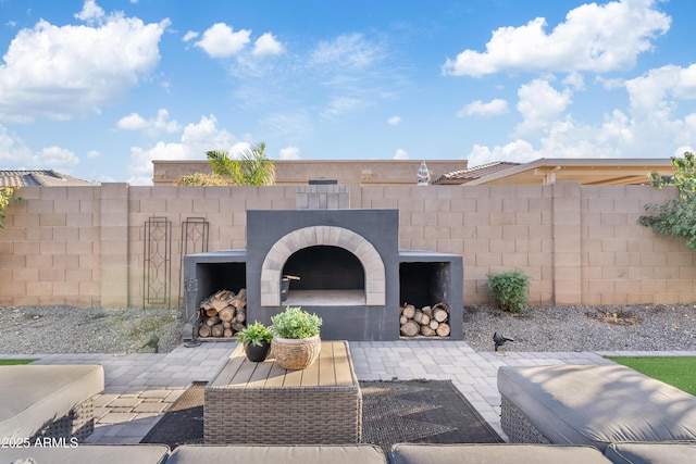 view of patio featuring an outdoor brick fireplace and fence