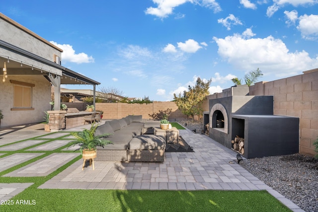 view of patio / terrace with a fenced backyard and an outdoor living space with a fireplace