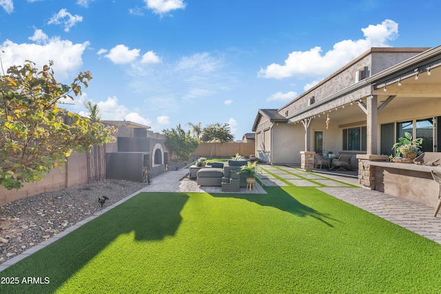 view of yard with an outdoor living space with a fireplace, a fenced backyard, and a patio