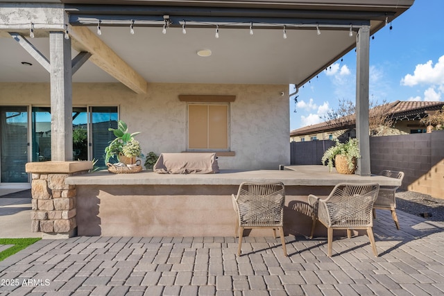 view of patio featuring outdoor dry bar and fence