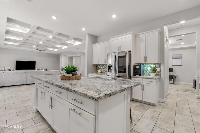 kitchen featuring light stone counters, a center island, white cabinets, and stainless steel fridge with ice dispenser