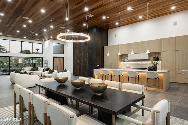 tiled dining room featuring sink, wood ceiling, and a high ceiling