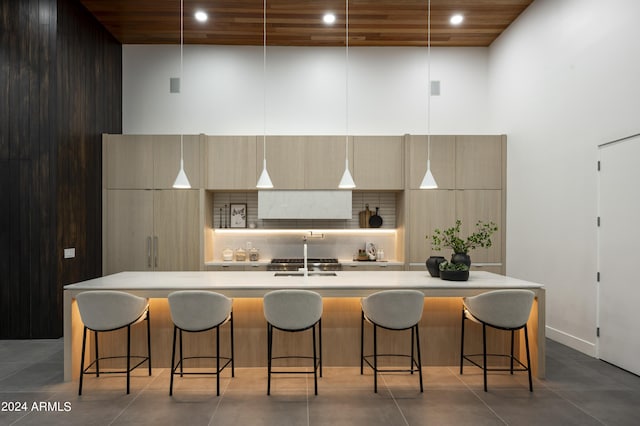 kitchen with a high ceiling, decorative light fixtures, decorative backsplash, and a spacious island