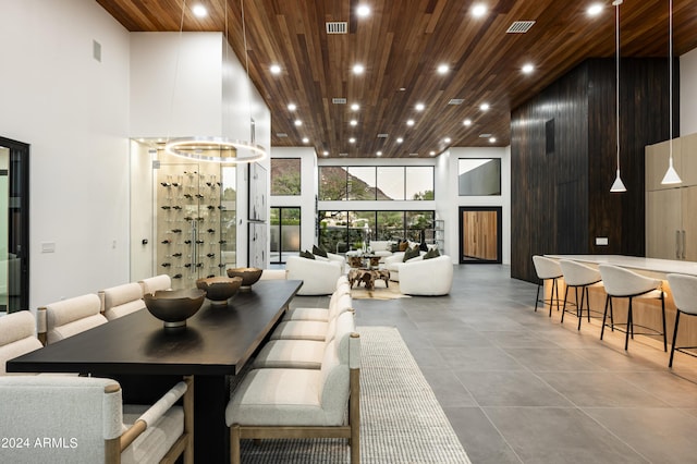 dining space featuring a towering ceiling, wooden walls, and wooden ceiling