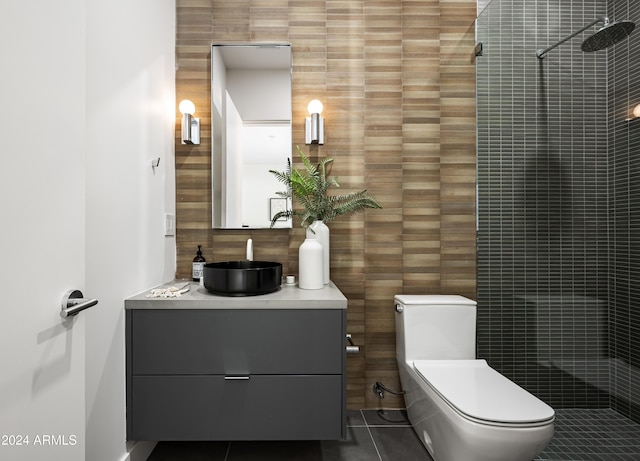 bathroom featuring toilet, tile walls, a tile shower, vanity, and tile patterned flooring