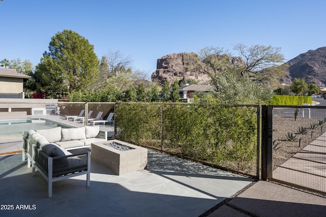 view of patio / terrace featuring a fenced in pool, a mountain view, and an outdoor living space with a fire pit