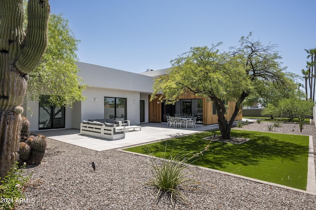 back of house with an outdoor living space, a patio, and a lawn