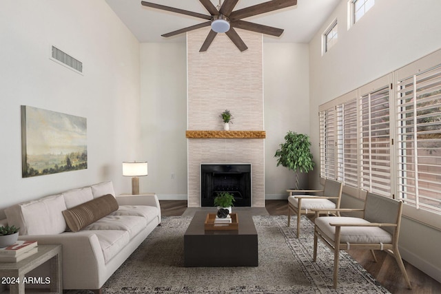 living room with a high ceiling, dark hardwood / wood-style floors, a tile fireplace, and plenty of natural light