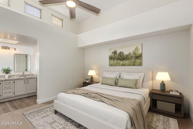 bedroom with ensuite bathroom, a towering ceiling, sink, ceiling fan, and light hardwood / wood-style flooring