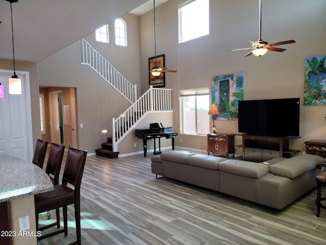 living room featuring a high ceiling, ceiling fan, and hardwood / wood-style floors