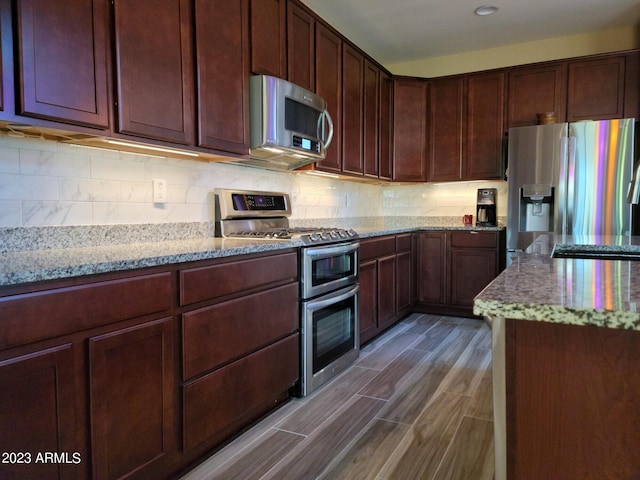 kitchen featuring backsplash, stainless steel appliances, and light stone countertops