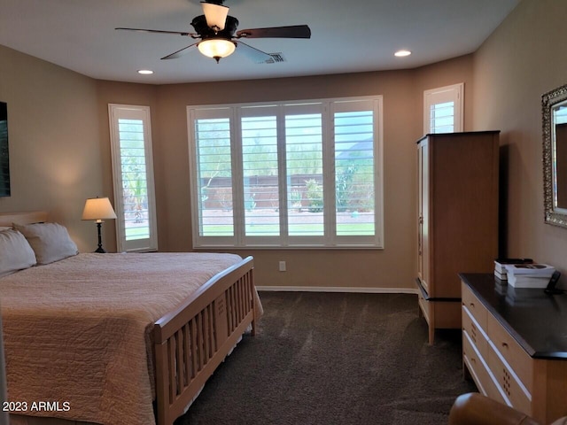 bedroom with dark carpet, ceiling fan, and multiple windows