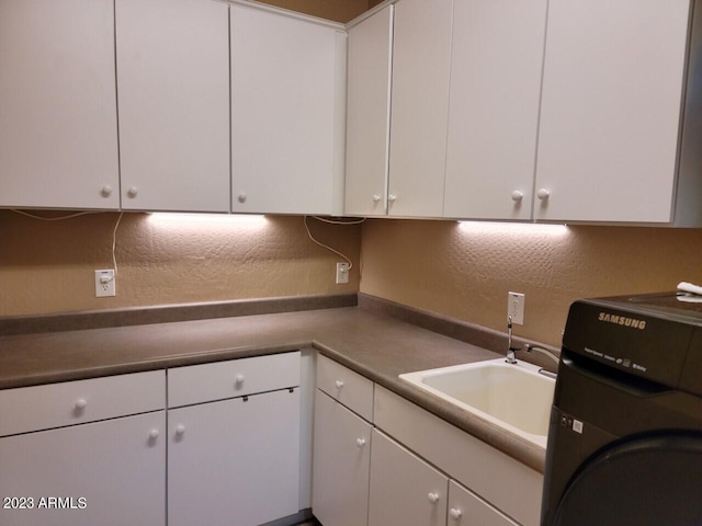 kitchen featuring washer / clothes dryer, white cabinetry, and sink