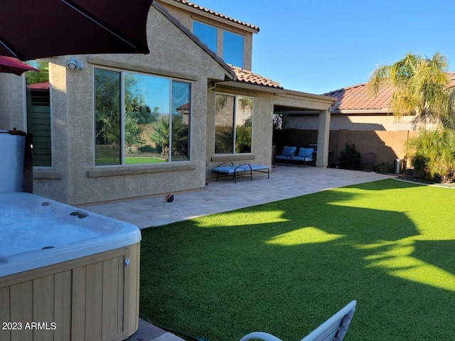 rear view of house with a hot tub and a patio