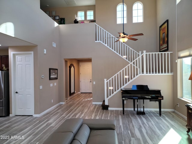 living room featuring ceiling fan, hardwood / wood-style floors, and a high ceiling