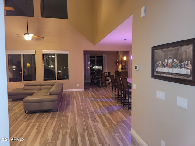 living room with hardwood / wood-style flooring, ceiling fan, and a high ceiling