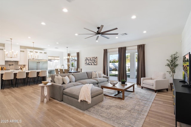 living room with light hardwood / wood-style flooring and ceiling fan with notable chandelier