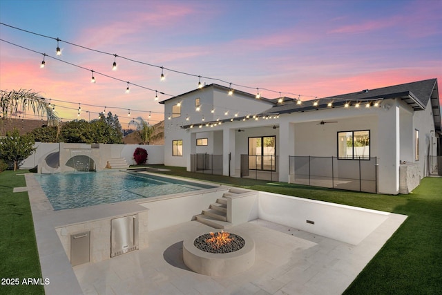 pool at dusk featuring a fire pit, area for grilling, a yard, and a patio area