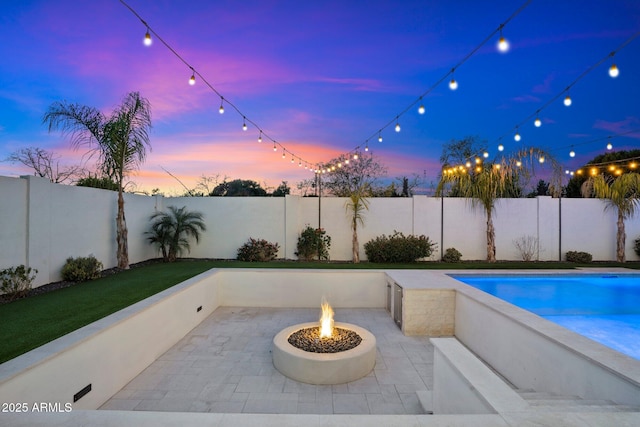 pool at dusk featuring an outdoor fire pit and a patio