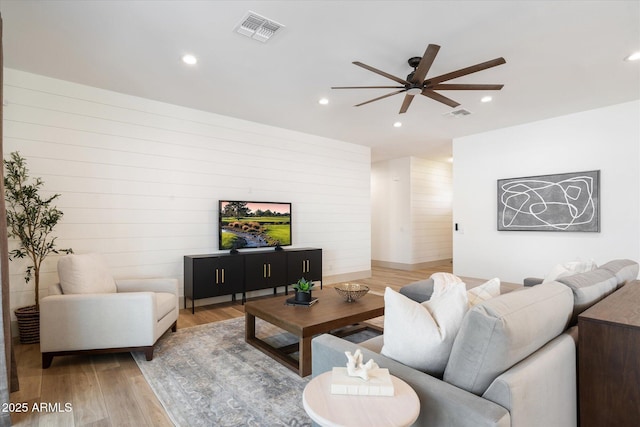 living room featuring ceiling fan, wooden walls, and wood-type flooring