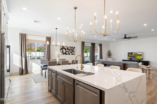 kitchen with sink, pendant lighting, stainless steel dishwasher, and ceiling fan with notable chandelier