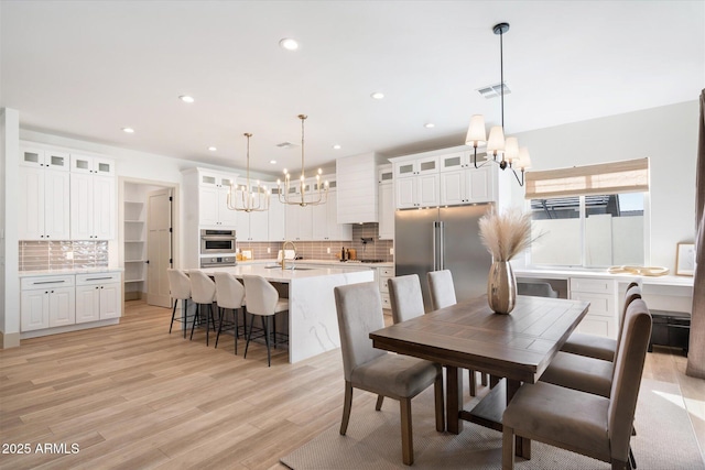 dining area featuring sink, light hardwood / wood-style floors, and an inviting chandelier