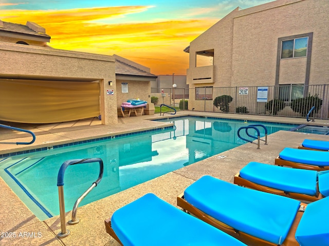 pool with a patio area and fence