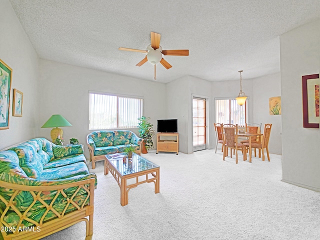 carpeted living room with a textured ceiling, a wealth of natural light, and a ceiling fan