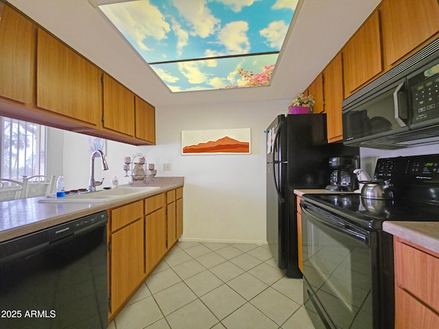 kitchen featuring brown cabinetry, light countertops, black appliances, a sink, and light tile patterned flooring