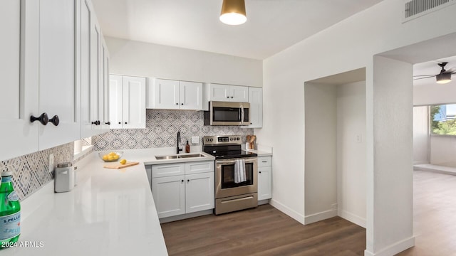 kitchen featuring backsplash, appliances with stainless steel finishes, white cabinetry, dark wood-type flooring, and sink